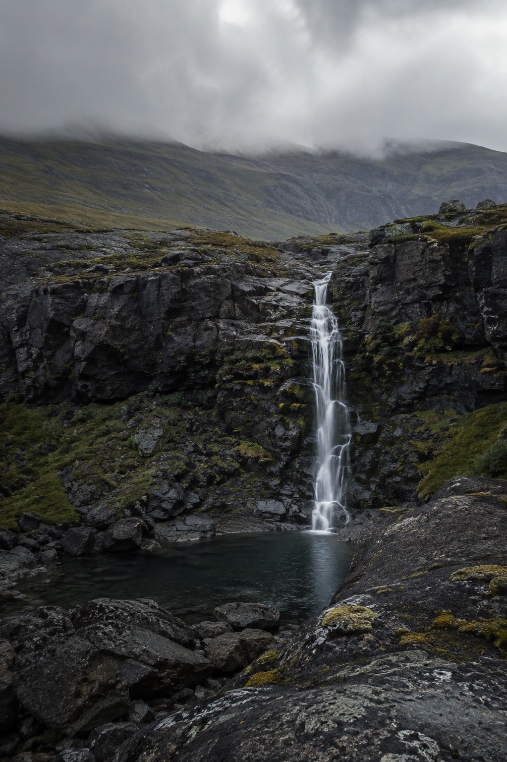 A narrow waterfall in a dark mountain valley
