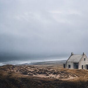 A solitary pale house stands beside a dark, windswept coast.