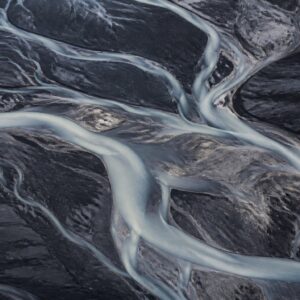 Pale tidal channels cross a dark mineral shoreline.